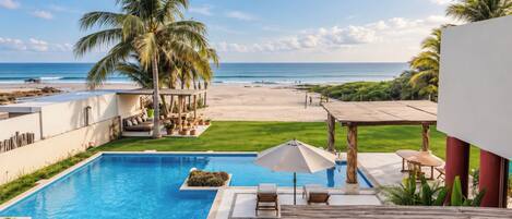 A pool area with a view of the beach and ocean.