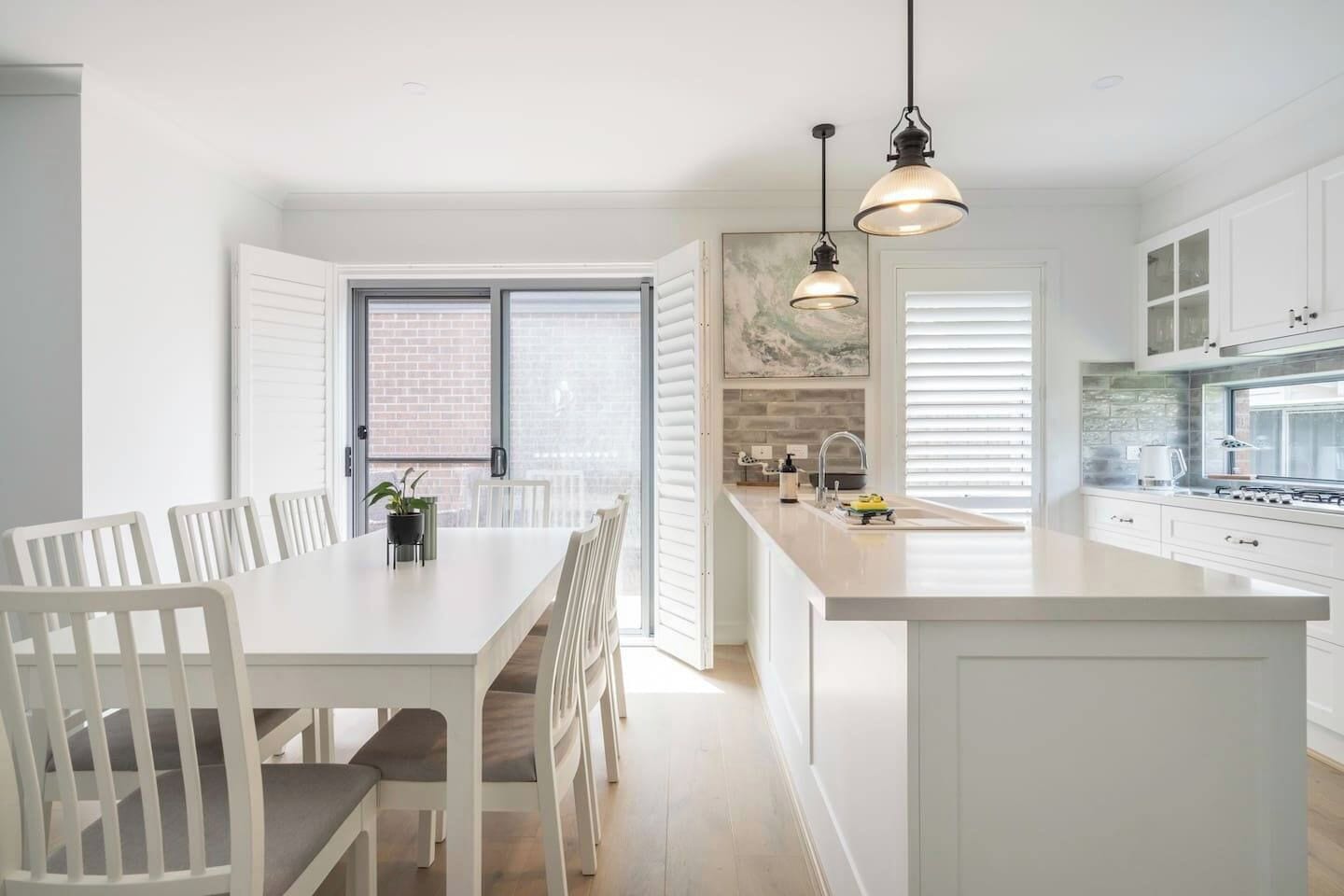 A modern kitchen with white cabinetry, a central island, and pendant lighting.
