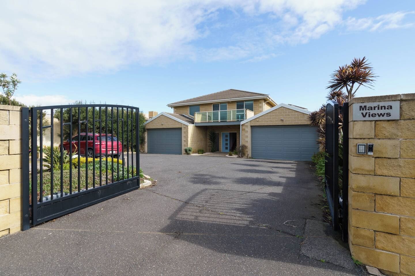 A gated residential area with a two-story house, a garage, and a driveway.