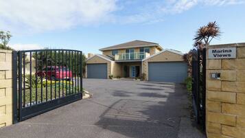 A gated residential area with a two-story house, a garage, and a driveway.