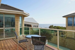 A balcony with a table and chairs, overlooking the sea. - Beachfront at Bonbeach A Coastal Lifestyle Gem (Bonbeach)