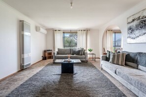 A living room with a sofa, a coffee table, and a TV. - Solanders Retro Residence Calming Days by the Sea (Dromana)