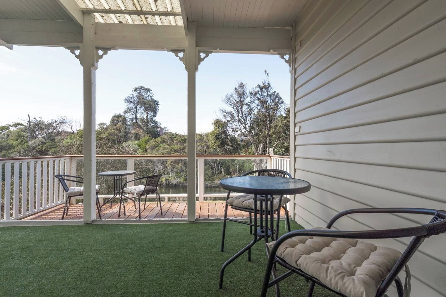 A covered outdoor area with a wooden deck, two tables, and chairs.