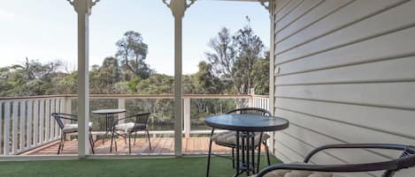 A covered outdoor area with a wooden deck, two tables, and chairs.