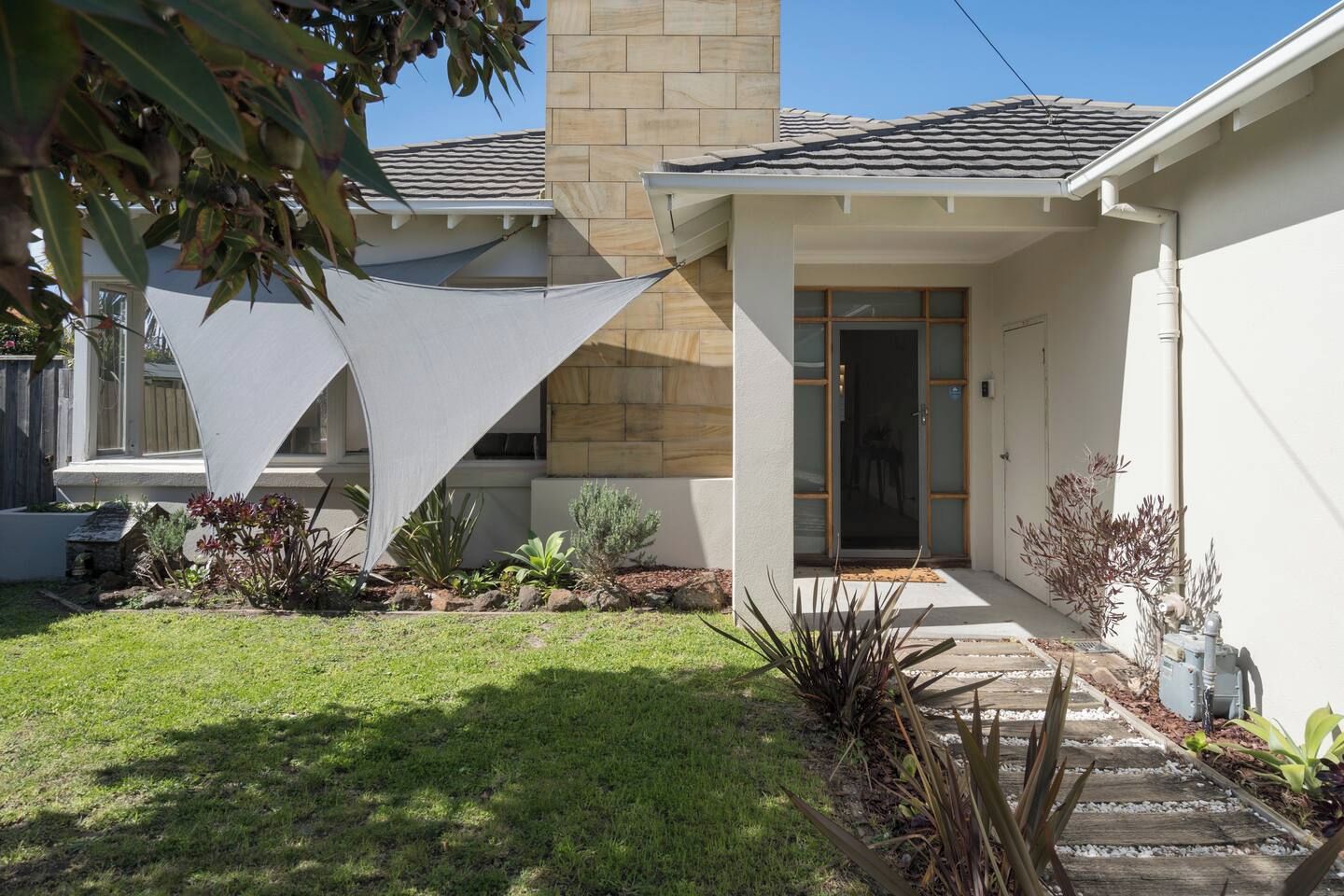 A modern house with a stone facade, a covered porch, and a well-maintained lawn.