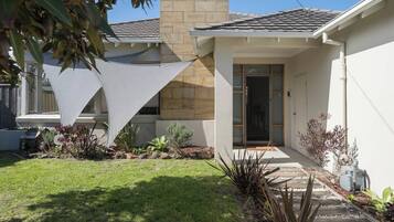 A modern house with a stone facade, a covered porch, and a well-maintained lawn.