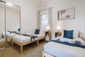 Ein Hotelzimmer mit zwei Betten, einem großen Spiegel, einem Gemälde und einem Fenster mit Vorhängen.