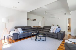 A modern living room with a sectional sofa, a round coffee table, and a floor lamp. - Willow Landing Beach House with Private Jetty (Frankston)