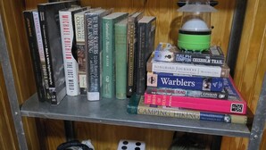 Une bibliothèque remplie de divers livres et un réchaud de camping.