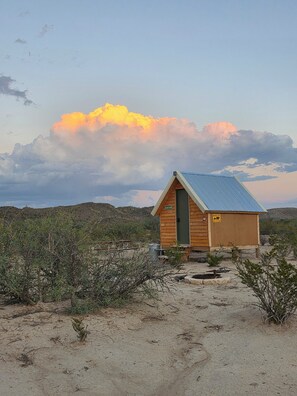Une petite cabane en bois, avec un toit en métal, une porte et un panneau indiquant l’entrée d’une grotte où vivent des ours.