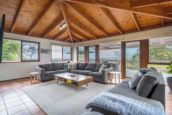 Amplia sala de estar con techo de madera alto, ventanas grandes y vista al exterior.