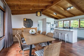 Una cocina moderna con armarios blancos, techo de madera y un ventanal con vistas a la vegetación.
