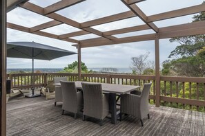 Terraza techada al aire libre con una mesa y sillas, con vistas a un paisaje pintoresco.