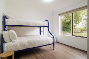A bunk bed with white bedding in a room with a large window and a small wooden stool. - McRae Hillside Terrace Panoramic Family Living (McCrae)