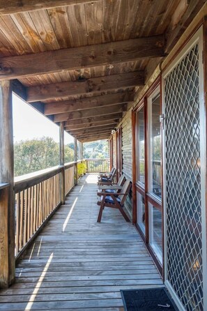 Une terrasse en bois dotée d’un espace abrité, de sièges et offrant une vue sur le paysage.