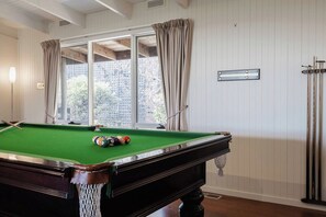Een biljart met ballen, een raam met gordijnen en een apparaat aan de muur.