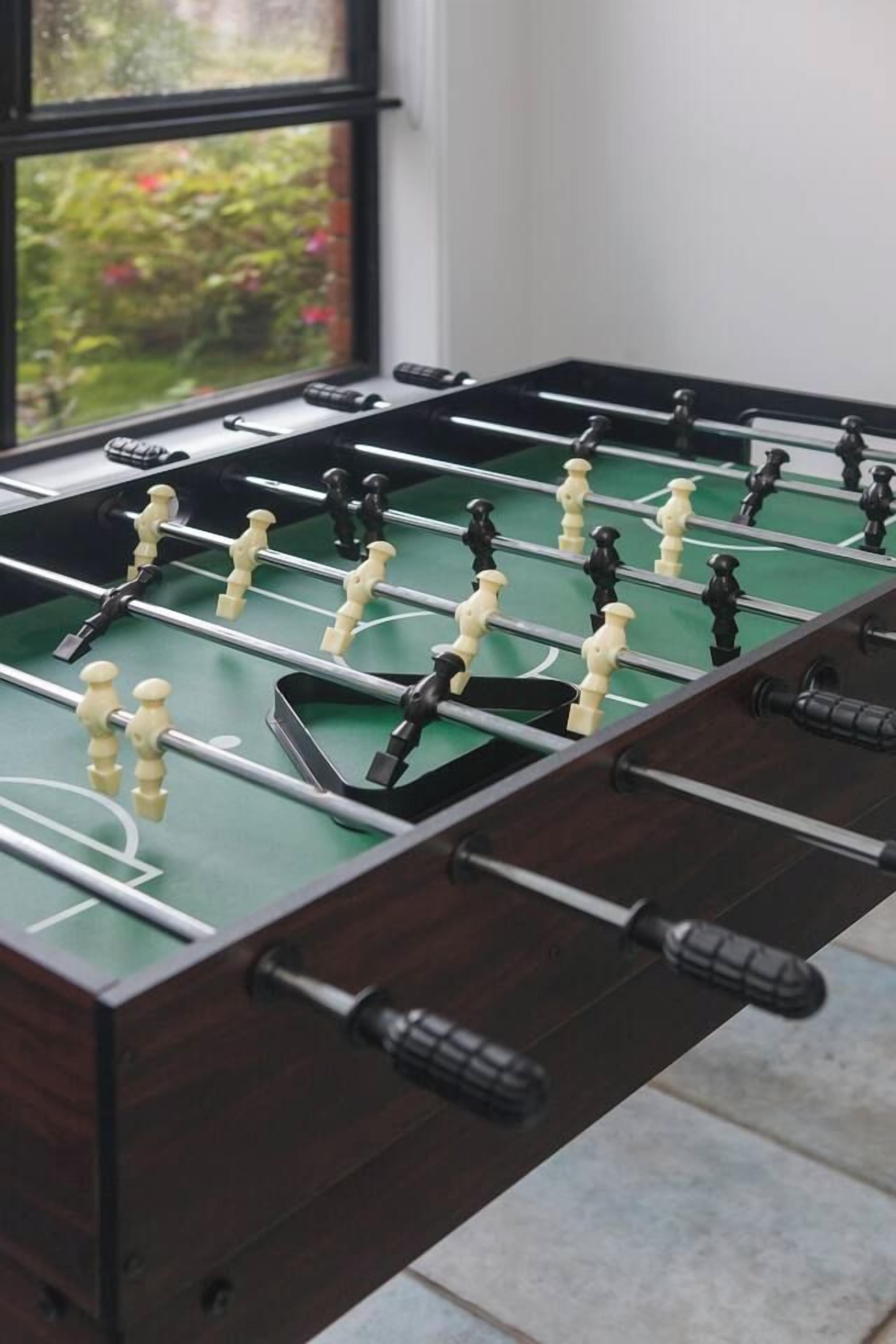 Une table de baby-foot avec un socle en bois foncé et une surface de jeu verte.