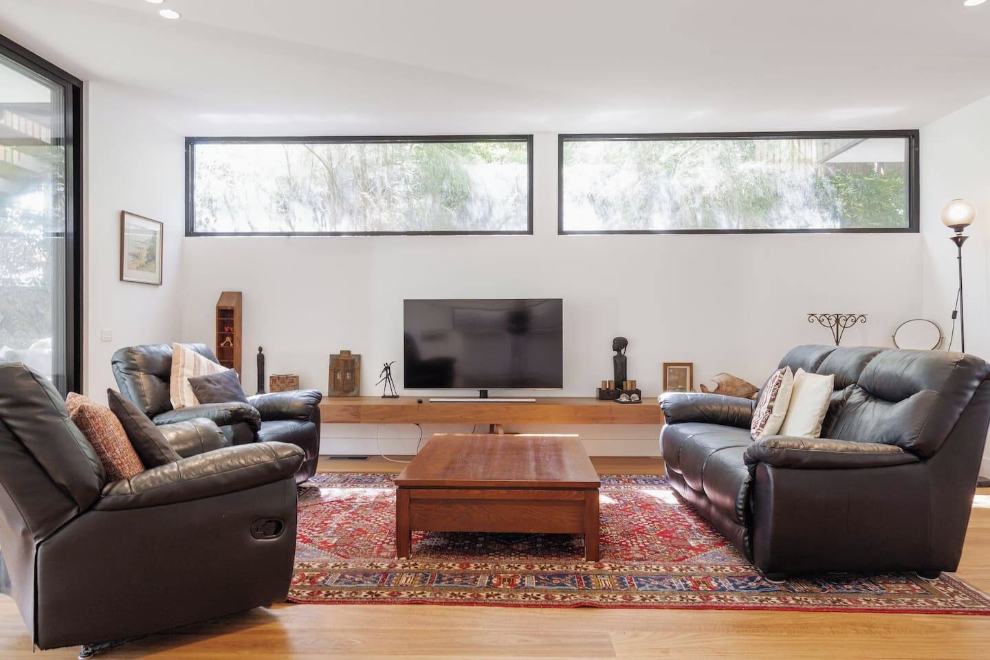 Een moderne woonkamer met leren banken, een houten salontafel en een flatscreen televisie.