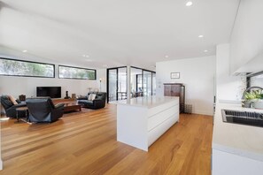 Een moderne woonkamer met een flatscreen televisie, leren banken en een houten vloer.