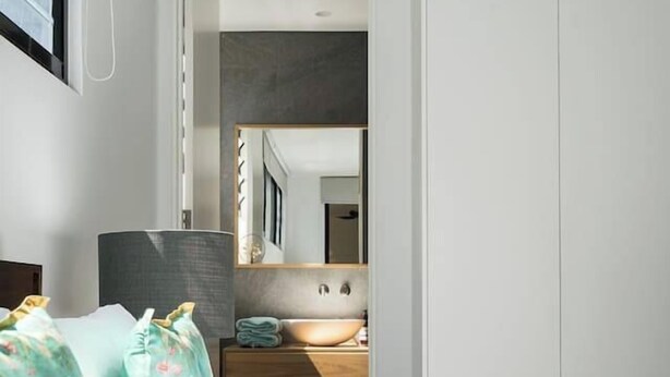 A modern bedroom with a bed, a bedside table, a mirror, and a wardrobe. - Ti Tree House Live like a Bonbeach Local (Bonbeach)
