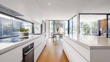 A modern kitchen with a central island, a dining area with a table and chairs, and large windows providing natural light and views.