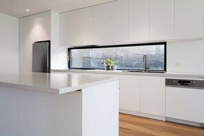 Een moderne keuken met witte kastjes, een ingebouwde vaatwasser en een raam met uitzicht op de stad.