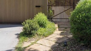 A modern house with a wooden exterior, a gated entrance, and a paved driveway. - Ti Tree House Live like a Bonbeach Local (Bonbeach)
