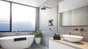 Un baño moderno con una bañera independiente, un lavamanos sobre encimera y una zona de ducha.