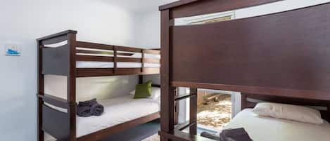 A bunk bed room with a window, a small rug, and a picture on the wall.