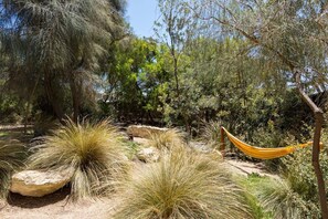 Un hamac installé dans un environnement naturel, avec des rochers et de l’herbe.