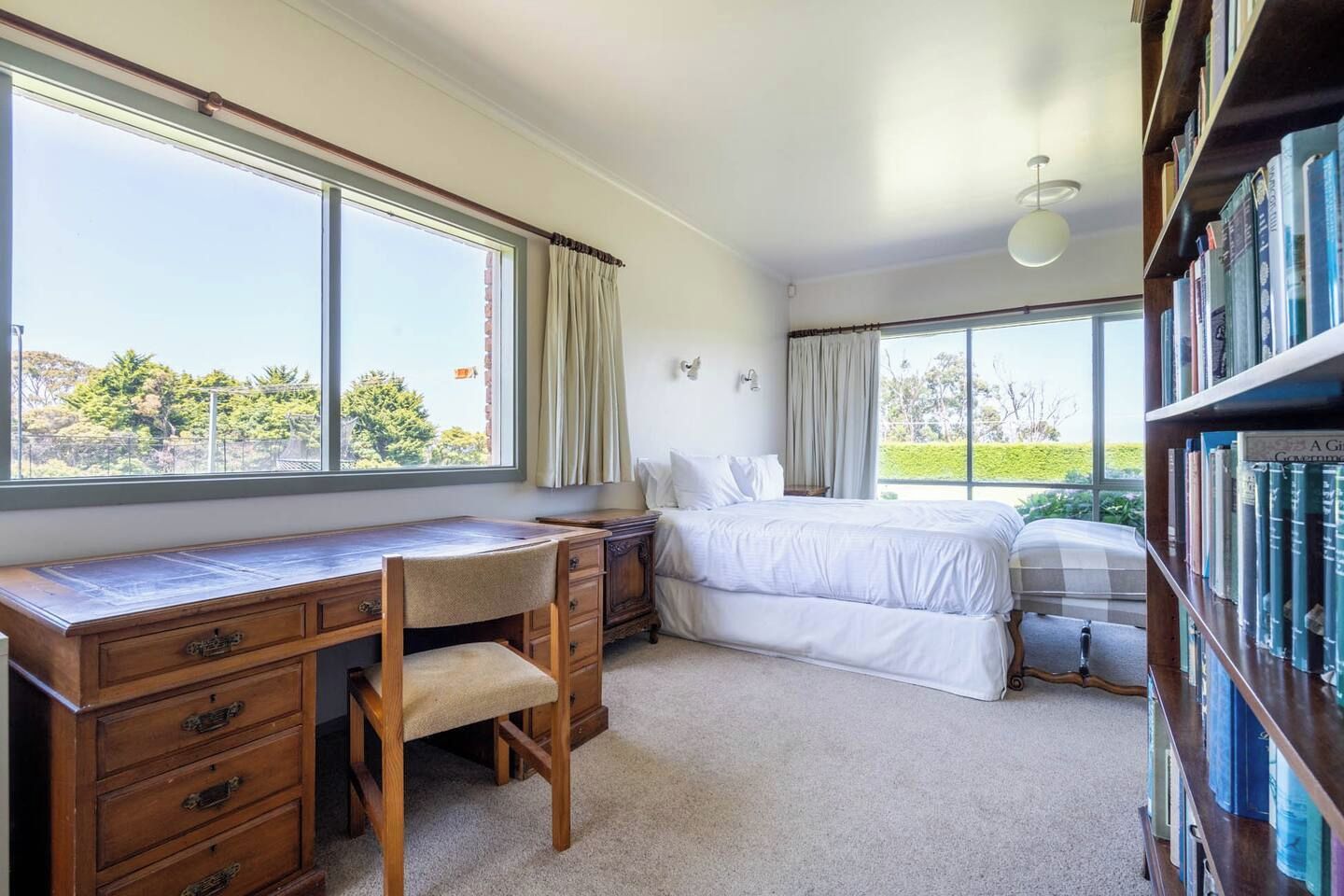 Une chambre avec un bureau, un lit et une bibliothèque.