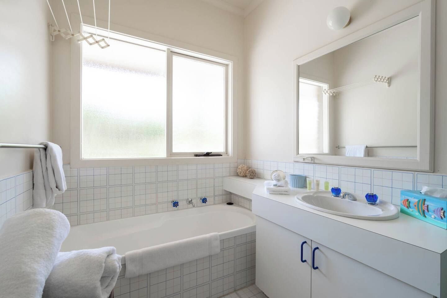 A bathroom with a bathtub, a sink, a mirror, and a window.