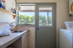 A compact kitchen with a window, a sink, and a laundry basket. - Viewbank Homestead A Sprawling Garden Estate (Shoreham)