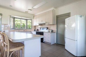 A modern kitchen with a central island, white cabinetry, a built-in oven, and a refrigerator. - Viewbank Homestead A Sprawling Garden Estate (Shoreham)