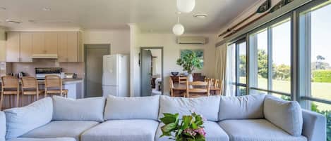 A modern living room with a large L-shaped sofa, a wooden coffee table, and a vase with flowers.