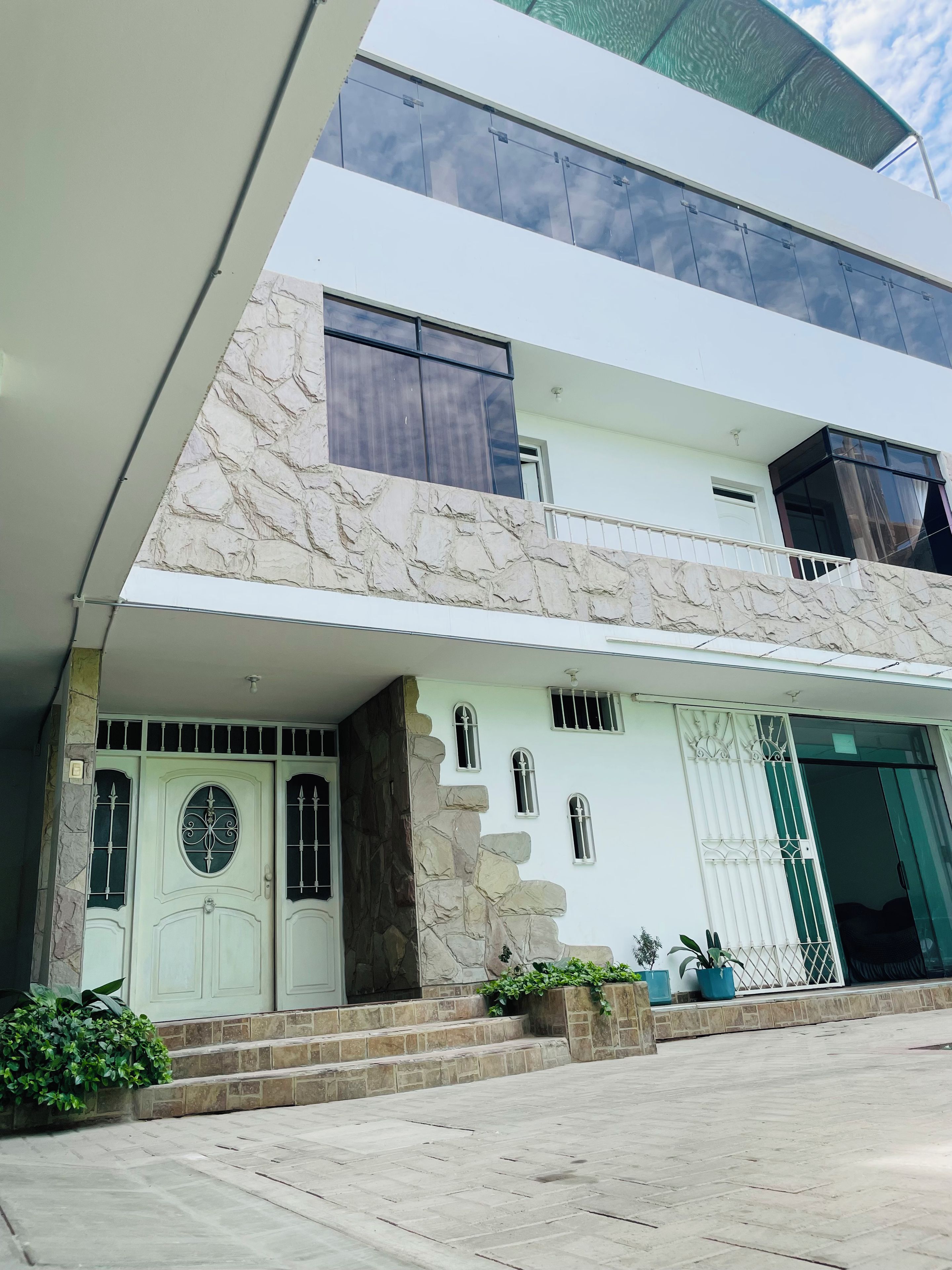 A modern two-story house with a stone facade, large windows, and a flat roof.