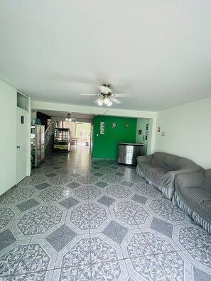 Amplia sala de estar con pisos de baldosas estampadas, ventilador de techo y pared verde decorativa.