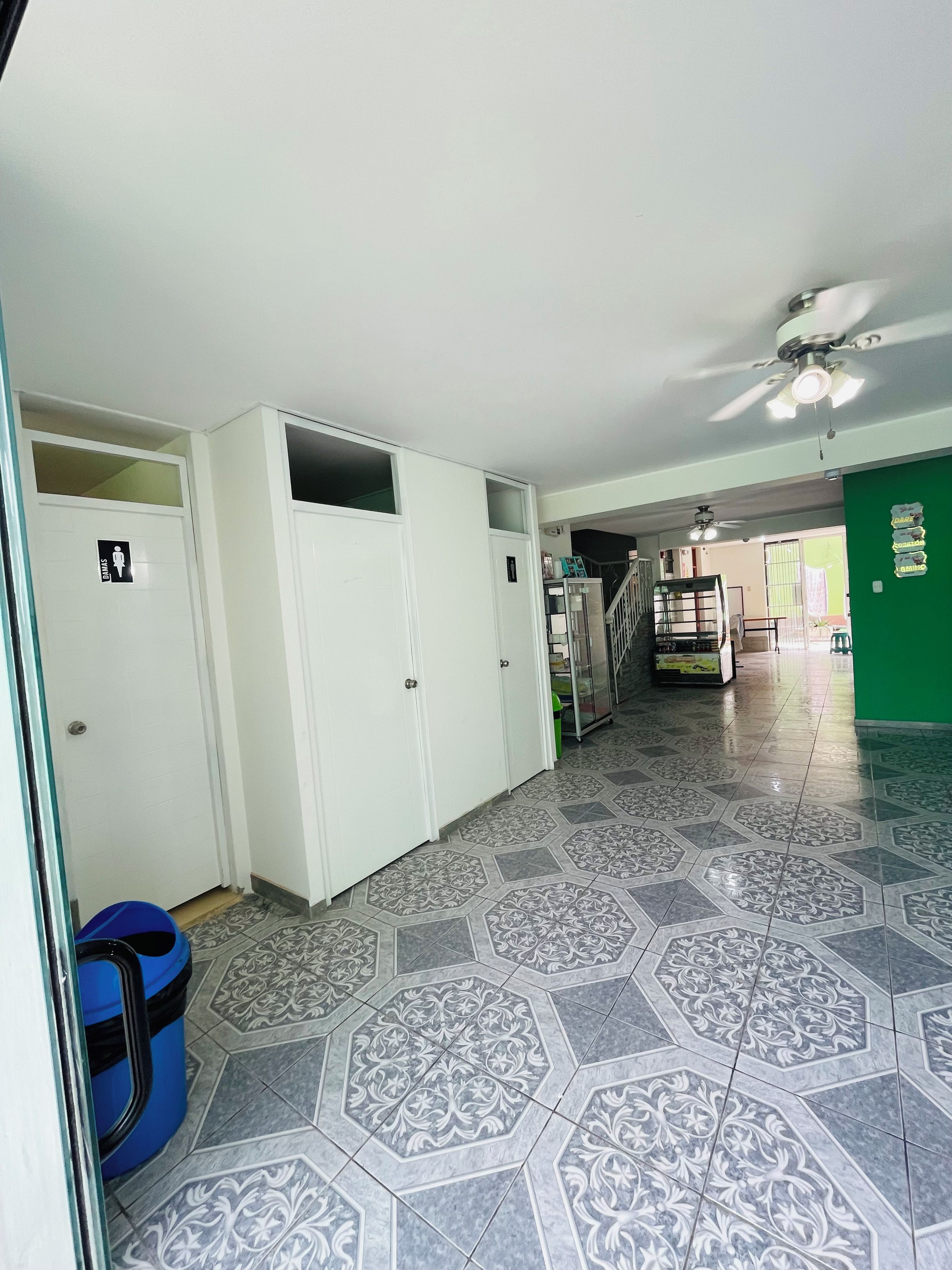 A hallway with patterned floor tiles, white doors, and a blue trash bin.