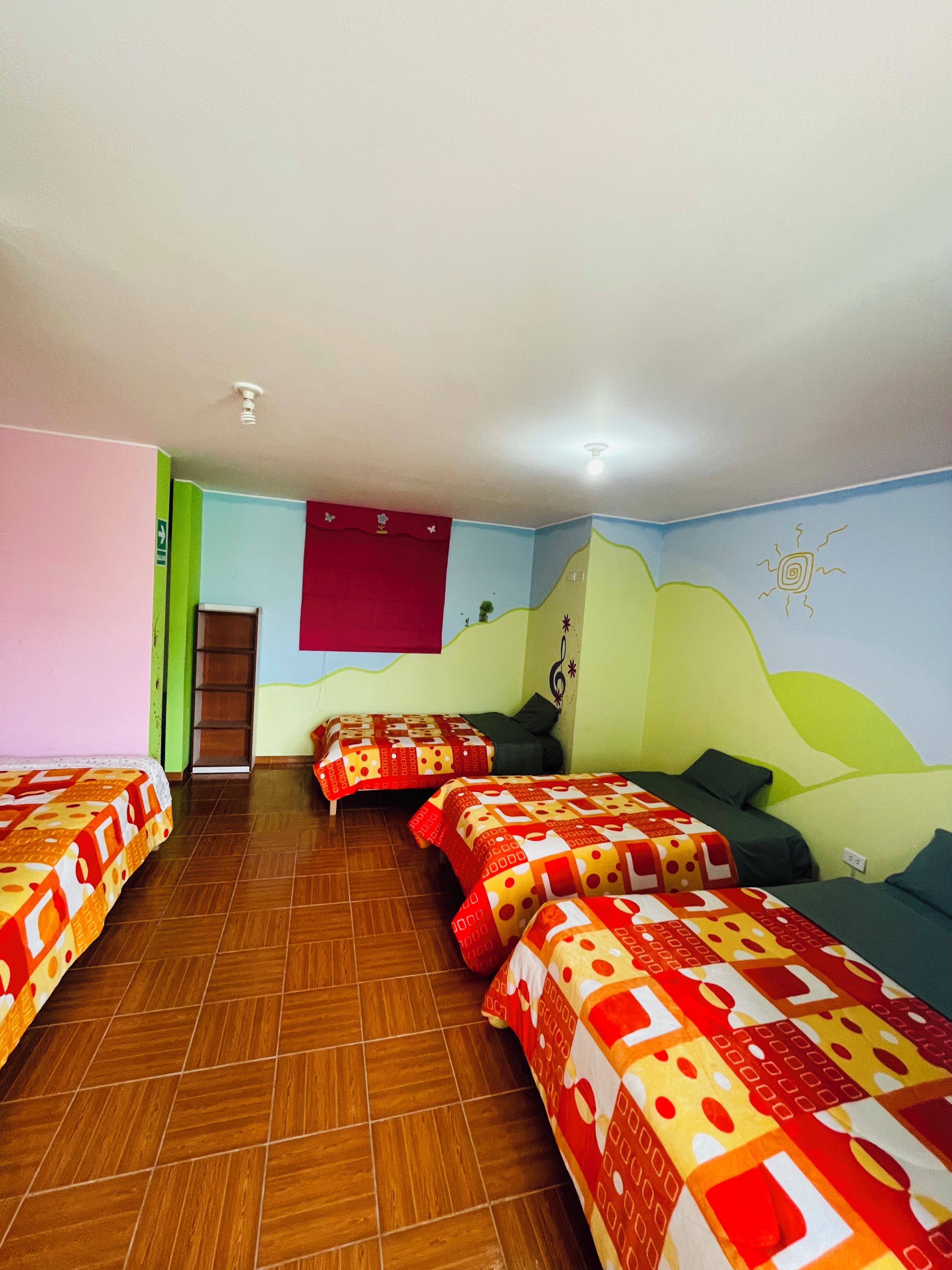 A room with four beds, a red wall, a green wall, and a mural.
