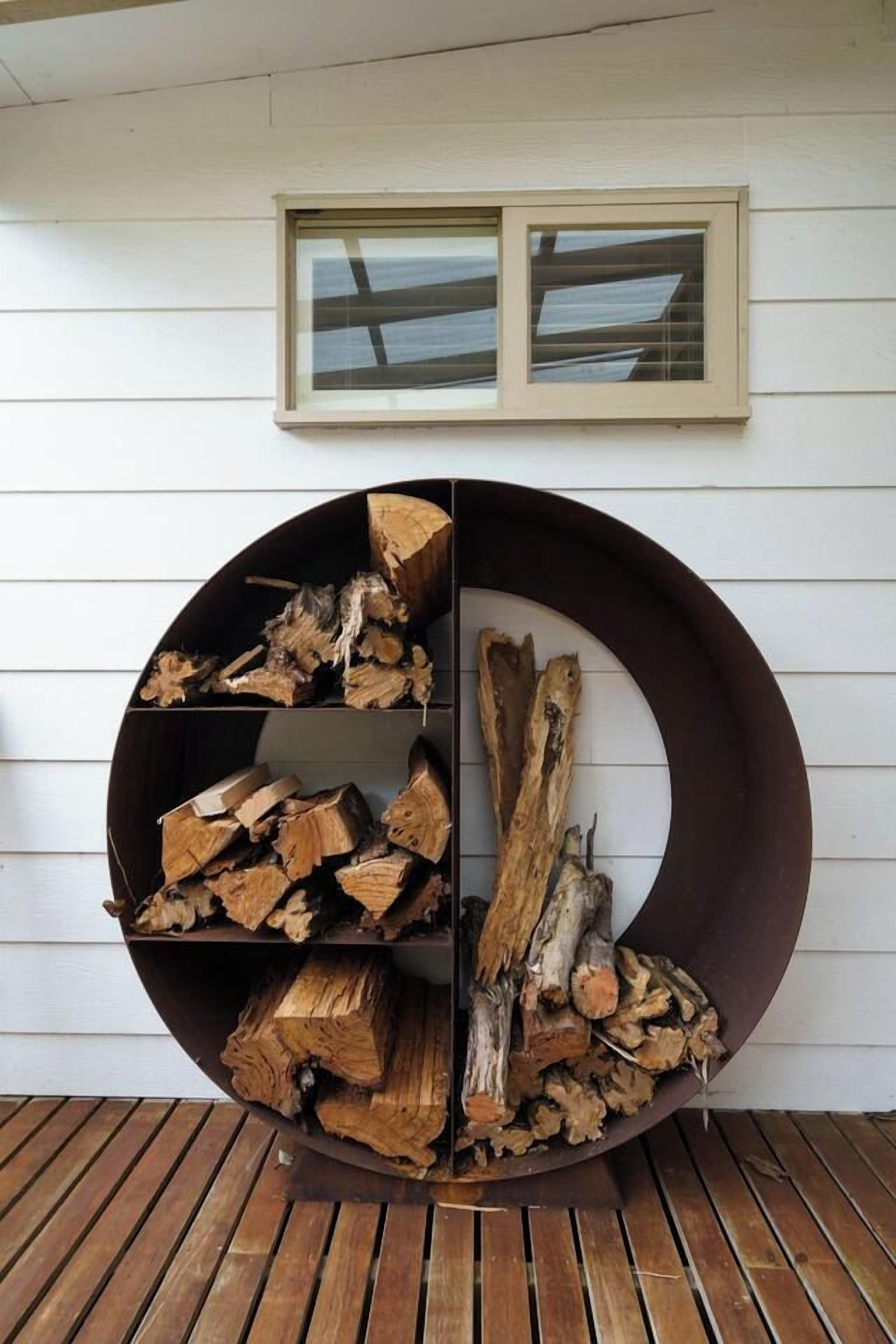 Une étagère circulaire en bois, ornée de bûches, avec une fenêtre au-dessus et une terrasse en bois.
