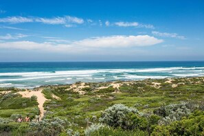A coastal landscape with a sandy beach, dense green vegetation, and a clear view of the ocean. - Doesntmatta Beachside Breeze at St Andrews Beach (Saint Andrews Beach)