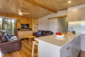 A modern cabin interior with a wooden ceiling, a leather sofa, a dining area, and a kitchen with a fruit bowl. - Doesntmatta Beachside Breeze at St Andrews Beach (Saint Andrews Beach)
