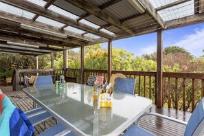 Eine Terrasse im Freien mit einem Tisch mit Glasplatte, Stühlen und einem Holzboden.