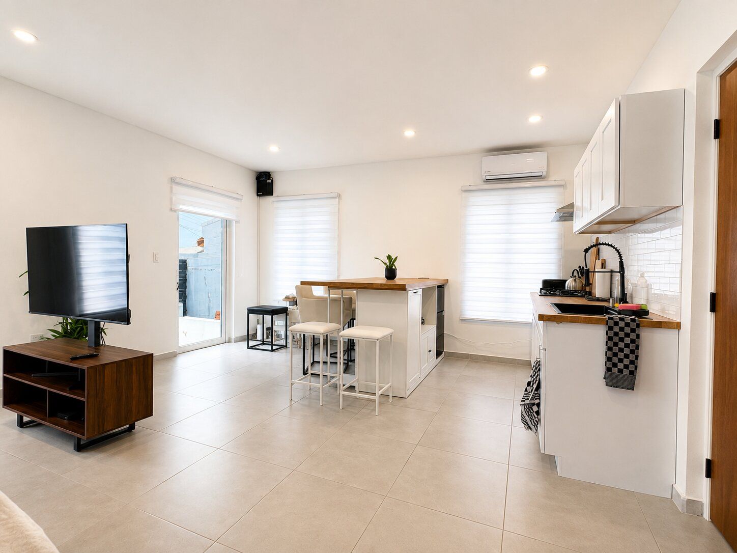 A modern kitchen with a dining area, a TV, and a small table with chairs.