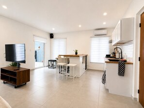 A modern kitchen with a dining area, a TV, and a small table with chairs. - Brand NEW Calishi Apartment; Comfort & Style (Oranjestad)