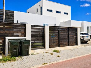 Ein modernes Wohngebäude mit weißer Fassade, einem Holzzaun und einem geparkten Auto.