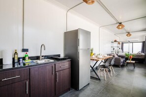 Una cocina moderna con armarios oscuros, un refrigerador de acero inoxidable y una zona de comedor con mesa y sillas.