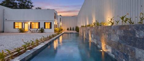 Un bâtiment moderne doté d’une piscine, d’un patio et d’un mur en pierre.