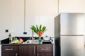 Una cocina moderna con armarios de madera oscura, un refrigerador de acero inoxidable y una encimera negra.