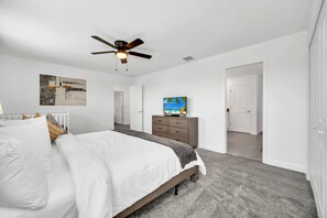 A bedroom with a bed, a ceiling fan, a TV on a dresser, and a door leading to another room. - Star Wars Game Room | Treehouse | Near Disney 9092 (Davenport)